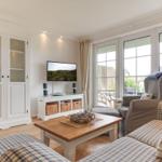 Living room with TV, sofa, and view of the garden.