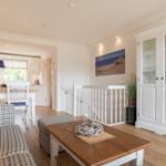 Living and dining area with wooden floor, white sofa, and dining furniture.