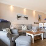 Living and dining area with sofa, armchair, and table.
