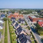 Luftbild einer Wohnsiedlung mit Häusern, Straßen und Blick auf das Meer.