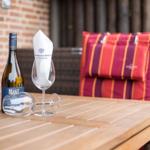Ein Tisch mit Weinflasche, zwei Gläsern und einem Kissen.