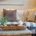 Ein Sofa mit Kissen und einem Holztablett mit Pflanze und Kerze.