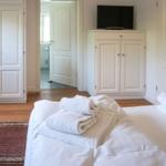 Bedroom with bed, towels, wardrobe, and TV.