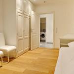 Bedroom with bed, desk, chairs, and wardrobe. Hallway to laundry room.