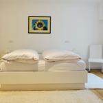 Bedroom with white bed, chair, and wall picture of sunflower.