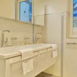 Bathroom with double sink, mirror cabinet, and window with beach picture.