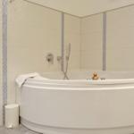 A bathtub with showerhead and yellow duck.