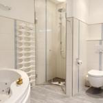 Bathroom with whirlpool, shower, and toilet. White tiles and gray floor tiles.