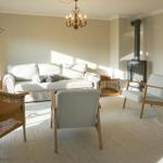 Living room with sofa, armchairs, and wood-burning stove. Hardwood and carpeted floor.
