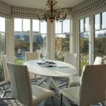 Round table with six chairs in dining room with large window view.