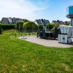 Backyard with grill area, seating group, and garden. View of residential houses.