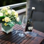 On the terrace, a table holds flowers, a champagne glass, and a bottle.