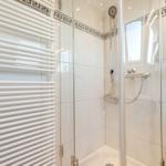 Shower with glass enclosure, heater, and mirror cabinet