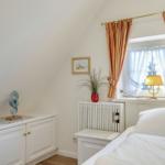 Bedroom with bed, window, curtains, and cabinet.