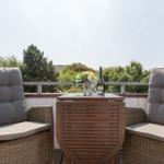 Terrace with two seating areas and table with flowers and bottle.