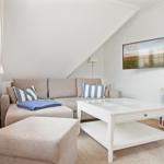 Living room with sofa, coffee table, and TV mounted on the wall.