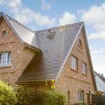 House with brick facade and black gabled roof under blue sky.