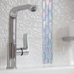 Modern sink with chrome faucet and mosaic tiles in the background.