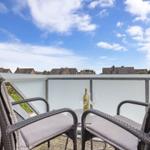 Terrace with two chairs and table, view of rooftops under blue sky.