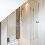 Shower with glass enclosure, brown tiles, and handheld shower