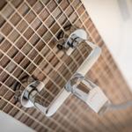 Shower head with chrome faucet on brown tiles