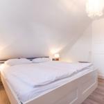 Bedroom with double bed, white nightstands, and a white wardrobe wall.