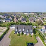 House with large garden and view of coastal landscape with houses and lighthouse.