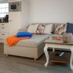 Living area with sofa, coffee table, and kitchen area in the background.