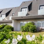 House with dormer windows and garden with white roses.
