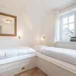 Zimmer mit zwei weißen Betten, Spiegel und Fenster mit Blick nach draußen.