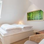 Schlafzimmer mit Doppelbett, Fenster und Wandbild mit Bambusmotiv.