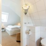 Badezimmer mit Toilette und Spiegel. Durchgang zu Schlafzimmer mit Dachfenster.