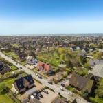 Aerial view of residential area near sea with houses and greenery.