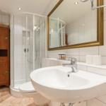 Badezimmer mit Dusche, Waschbecken und Spiegel