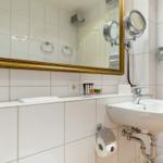 Badezimmer mit Waschbecken, Spiegel und Duschvorhang
