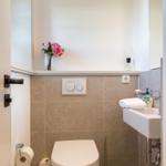 Badezimmer mit Toilette, Waschbecken und Blumenarrangement.
