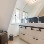 Badezimmer mit Waschbecken, Spiegel und Fenster
