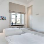 Schlafzimmer mit Doppelbett, Fenster und Wandbild.