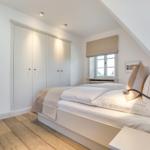 Schlafzimmer mit Doppelbett, Kleiderschrank und Fenster unter Dachschrägen.