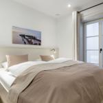Schlafzimmer mit Doppelbett, Fenster und Wandbild.
