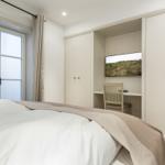 Schlafzimmer mit Bett, Schreibtisch und Fernseher.