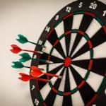 Dartboard mit vier Pfeilen an der Wand