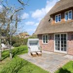 Haus mit Strohdach, Terrasse und Strandkorb im Garten.