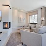 Wohnzimmer mit Sofa, Kamin und Fernseher an der Wand.