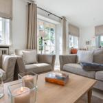 Wohnzimmer mit Sofa, Sessel und Tisch mit Kerzen und Buch.