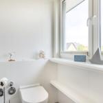 Bathroom with toilet, heater, and window with view.