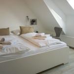 Bedroom with sloped ceiling, bed, chair, and skylight.