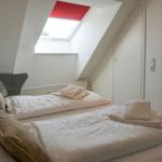 Attic room with sloped ceiling, double bed, and skylight with red blind.