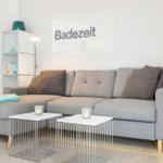 Gray sofa with cushions and two tables against wall with flag.