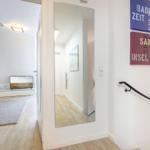 Entrance with mirror and wall art. View into living room with TV.